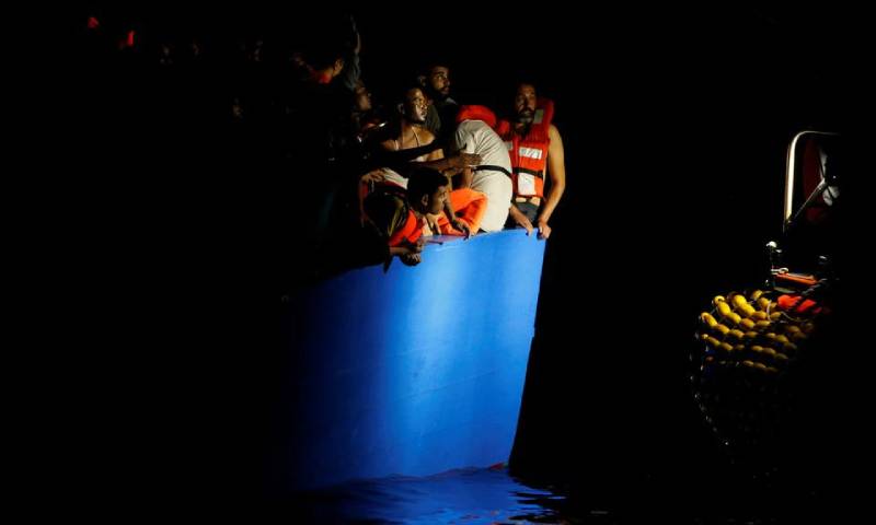 مهاجرون على متن قارب خشبي مكتظ ينتظرون إنقاذهم من قبل سفينة إنقاذ المهاجرين التابعة لمنظمة غير حكومية ألمانية (رويترز)