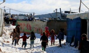 أطفال سوريون يركضون وسط الثلوج في مخيم الهلال للاجئين السوريين في قرية الطيبة بالقرب من بعلبك في سهل البقاع اللبناني - 20 كانون الثاني 2022 (AFP)
