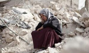 سيدة سورية تجلس على أنقاض منزلها في طريق الباب بمدينة حلب
 (AFP) 