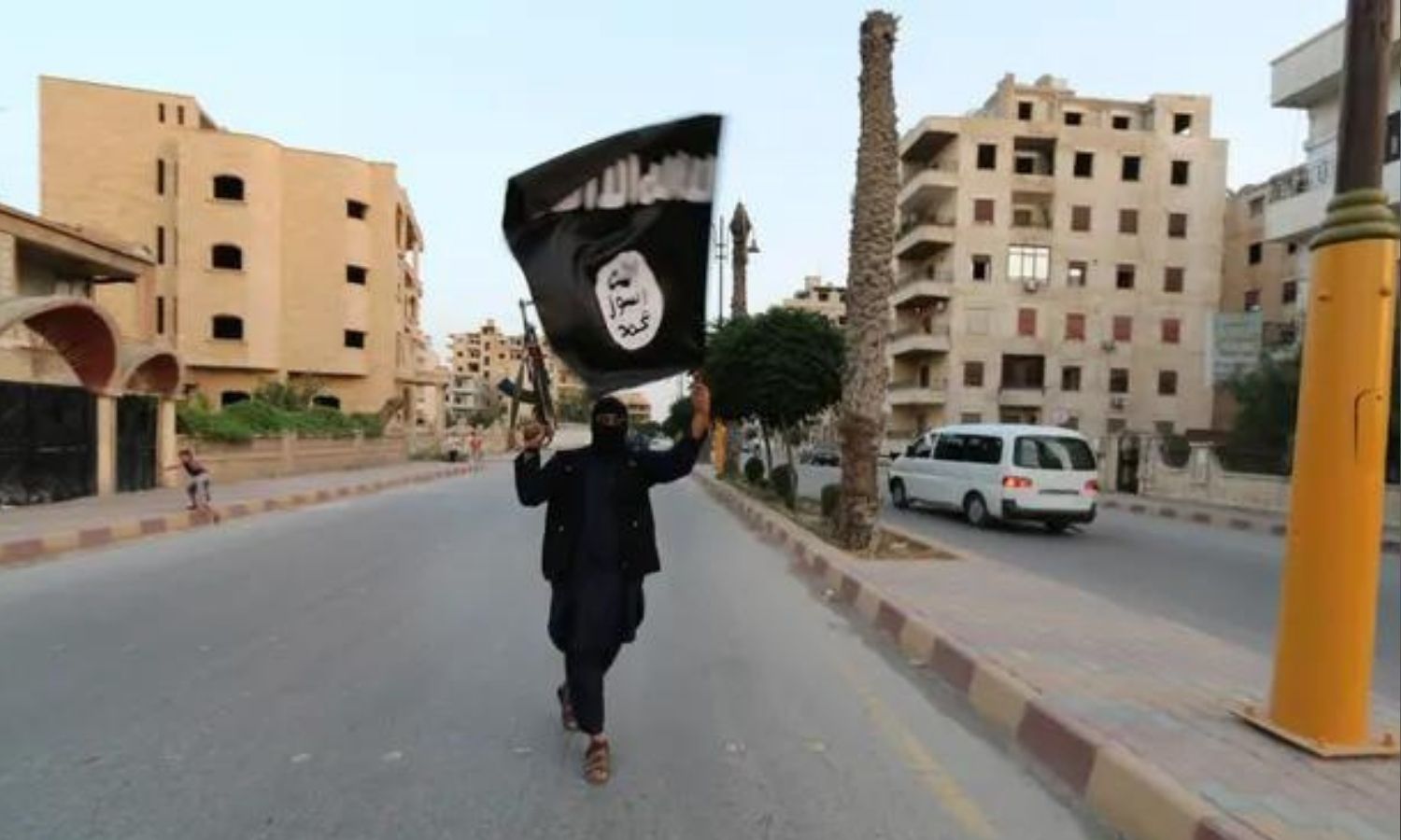 مقاتل من "تنظيم الدولة الإسلامية" يلوح بعلم التنظيم في الرقة (رويترز)