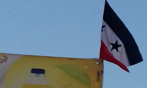 علم النظام السوري الذي رفعه مجهولون على إحدى اللوحات الإعلانية شرقي دير الزور، 6 من آذار 2022 (مراسل الشرقية/ فيس بوك)