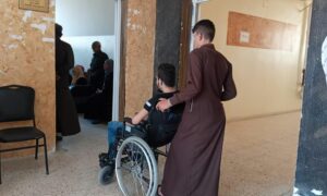 شاب برفقة شخص من ذوي الإعاقة داخل دائرة حماية المستهلك في مدينة الرقة شمال شرقي سوريا- شباط 2021 (موقع 