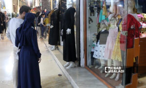 مارة أمام أحد متاجر الألبسة في مدينة إدلب (عنب بلدي/ أنس الخولي) 