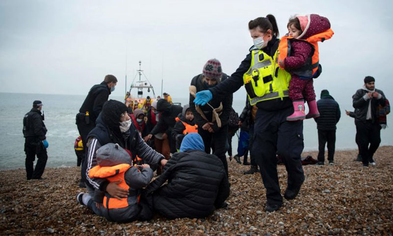 عضو في قوة الحدود البريطانية يساعد الأطفال المهاجرين على شاطئ في دونجينيس على الساحل الجنوبي الشرقي لإنجلترا- 24 من تشرين الثاني 2021 (AFP)