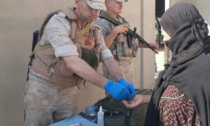 جندي روسي يوزع أدوية على مدنيين في بلدة خشام شرقي درعا (هنا دير الزور/ فيس بوك)