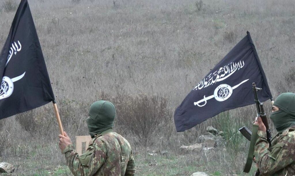 مقاتلان يحملان راية تنظيم "حراس الدين" في ريف إدلب (مؤسسة شام الرباط)