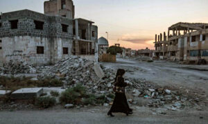 سيدة سورية تسير في إحدى شوارع مدينة الرقة المدمرة بعد معارك عسكرية مع تنظيم 