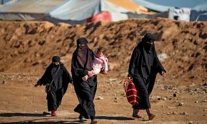 نساء وأطفال يمشون في مخيم احتجزت فيه عائلات مقاتلي 