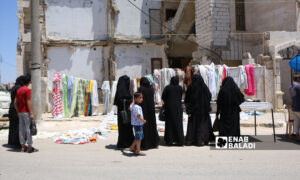 سيدات سوريات أمام إحدى بسطات بيع الألبسة في مدينة إدلب شمال غربي سوريا- 21 من حزيران 2022 (عنب بلدي)
