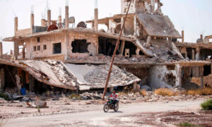 رجل يركب دراجة نارية بالقرب من المباني المدمرة في مدينة درعا جنوبي سوريا- 2 تشرين الأول 2018 (AFP)