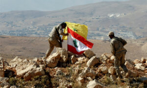 مقاتلون يضعون العلم اللبناني إلى جانب علم حزب الله في جرود عرسال على الحدود مع سوريا- 25 من تموز 2017 (رويترز)