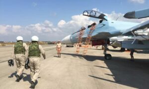 طياران يتوجهان إلى طائرة حربية روسية في قاعدة حميميم العسكرية (سبوتنيك)