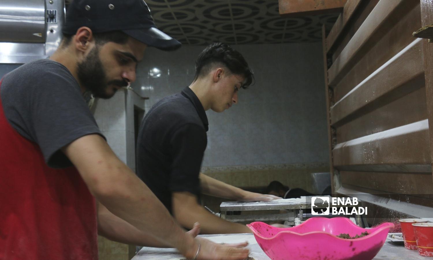 شابان يعملان في مخبز للمعجنات في السوق المسقوف بمدينة إعزاز بريف حلب الشمالي - 2 أيلول 2022 (عنب بلدي / ديان جنباز)