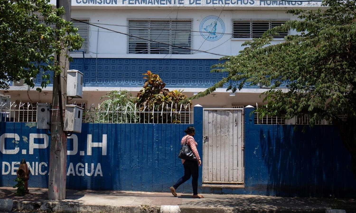 امرأة تمشي بجوار مكتب اللجنة الدائمة لحقوق الإنسان في نيكاراغوا، الذي أغلق بعد أن بقرار من برلمان البلاد طال 25 منظمة غير حكومية انتقدت الحكومة (رويترز)