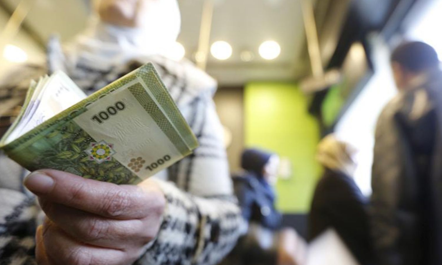 سيدة تحمل فئات من العملة السورية داخل محل صرافة في دمشق (رويترز)