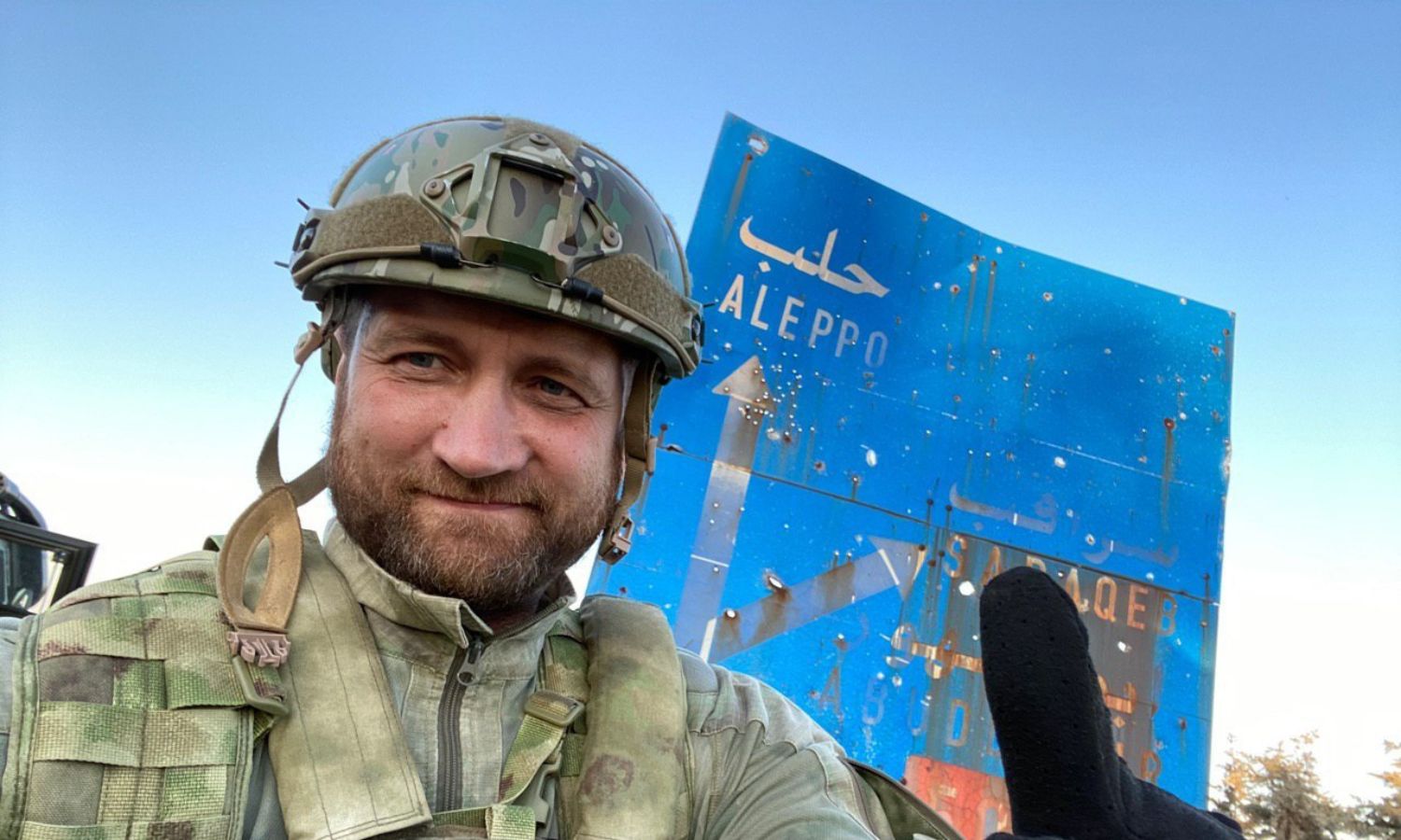 المقاتل والمراسل الحربي الروسي أوليغ بلوخين قرب لافتة كُتب عليها حلب- 14 من آب 2020 (حساب المراسل في تويتر)