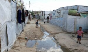 أطفال سوريون لاجئون يقفون قرب مجرى المياه في مخيم في سهل البقاع اللبناني- 18 من تشرين الأول 2022 (رويترز)