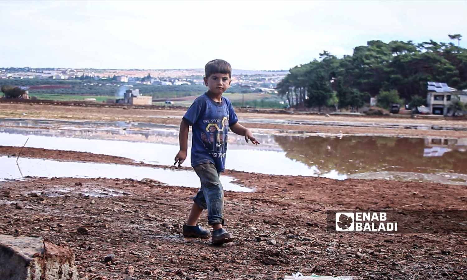 طفل يمشي  بالقرب من تجمع مياه الأمطار في مخيم السكة  بسهل الروج في ريف إدلب- 21 تشرين الأول 2022 (عنب بلدي/ محمد نعسان دبل)