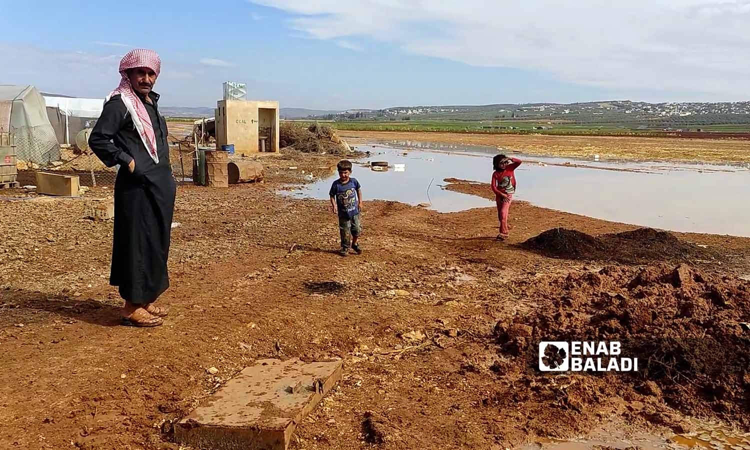 أحد سكان المخيم يقف بالقرب من تجمع مياه الأمطار في مخيم السكة  بسهل الروج في ريف إدلب- 21 تشرين الأول 2022 (عنب بلدي/ محمد نعسان دبل)