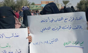 امرأة ترفع لافتة معارضة لقرار منع الحجاب في المدارس بمناطق 