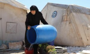 مسنّة نازحة تملأ دلوًا بالمياه في مخيم بشمال غربي سوريا - أيلول 2021 (أطباء بلا حدود)