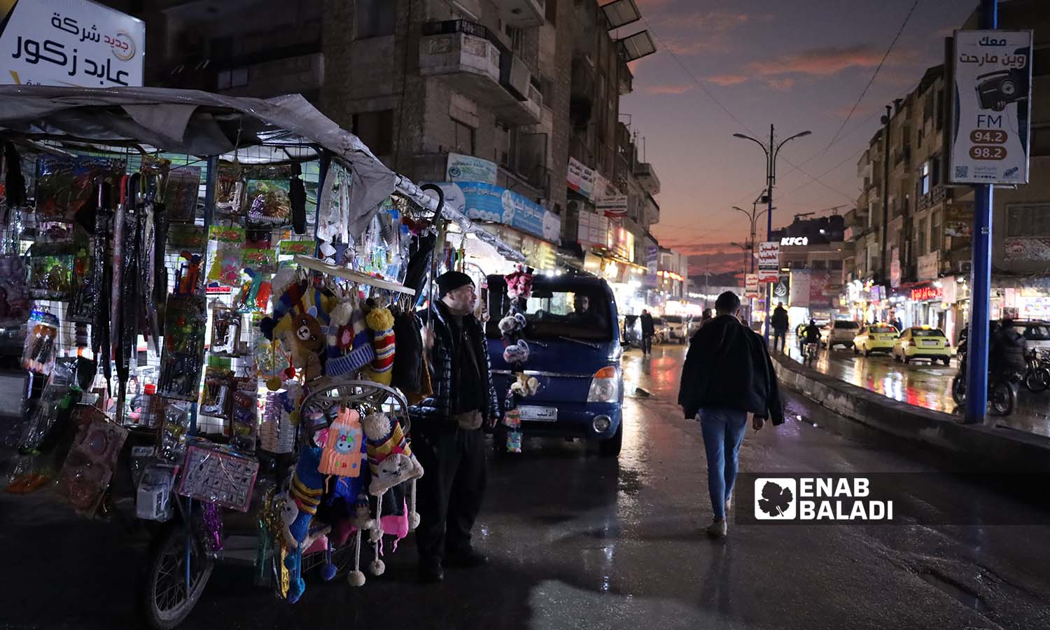 رجل يمشي وسط الشارع بالقرب من بائع متجول في سوق مدينة إدلب- 25 من تشرين الثاني 2022 (عنب بلدي/ مجد هامو)
