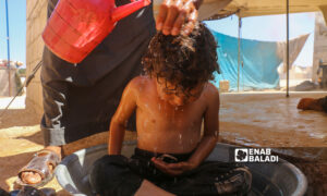 طفل يستحم في أحد المخيمات شمالي إدلب- تموز 2022 (عنب بلدي/ إياد عبد الجواد)
