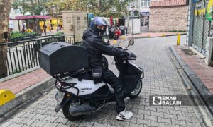 عامل توصيل طلبات يركب دراجته النارية لتوصيل طلبات الزبائن_ 29 من تشرين الثاني 2022 (عنب بلدي)