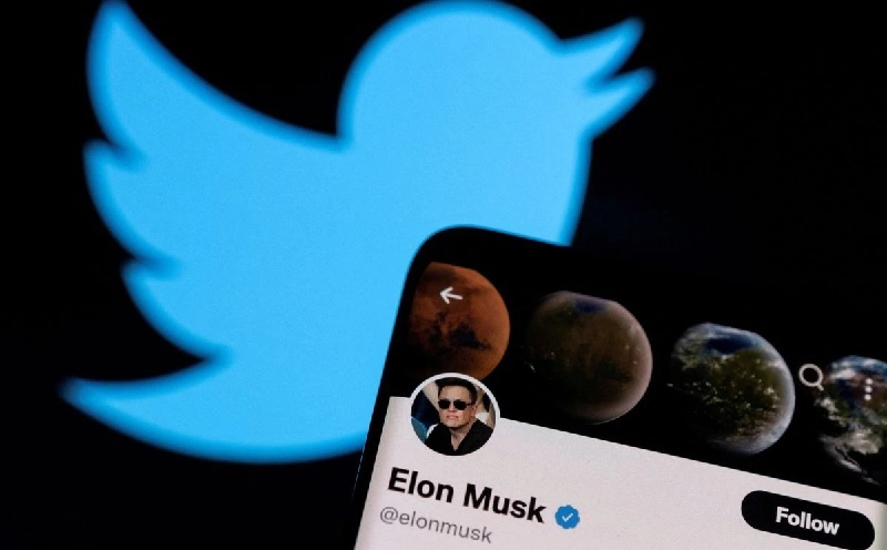 حساب إيلون ماسك على "تويتر" على هاتف ذكي أمام شعار "تويتر"، 15 نيسان 2022. رويترز