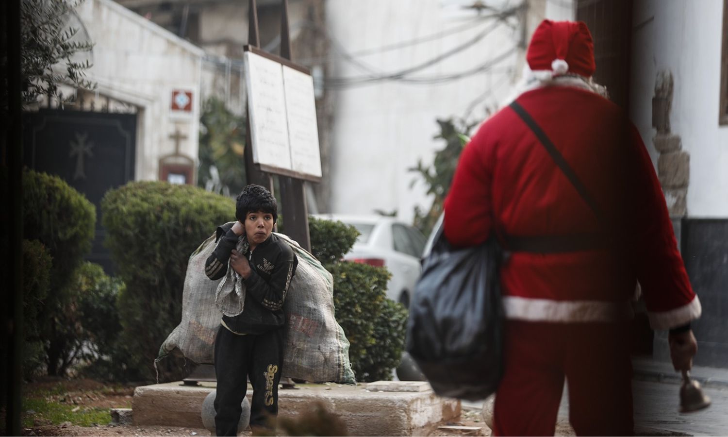 "بابا نويل" يحمل كيس هدايا وأمامه طفل يحمل كيس لجمع النفايات القابلة لإعادة التدوير في منطقة باب شرقي في دمشق- 11 من كانون الأول 2022(إنستجرام/عمر صناديقي)