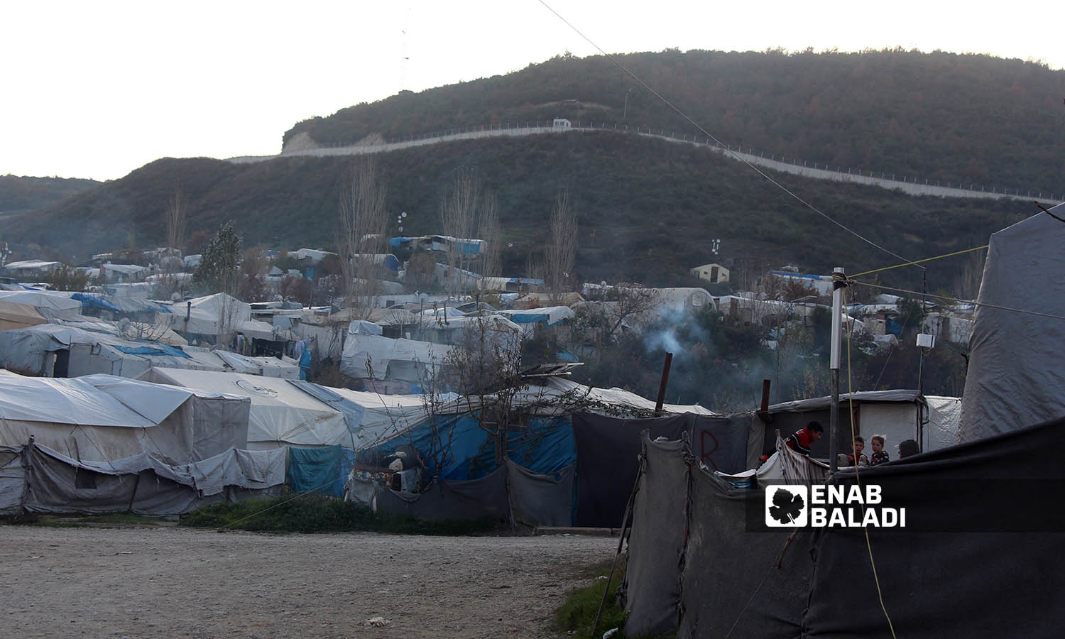 مشهد عام لمخيم خربة الجوز ومن خلفه الجدار الفاصل على الحدود السورية التركية- 23 من كانون الأول 2022(عنب بلدي/ إياد عبد الجواد)