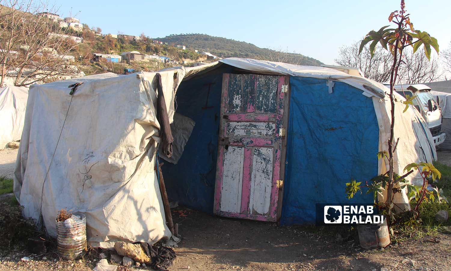 خيمة سكنية مكونة من الشوادر والنايلون مزودة بباب خشبي في مخيم خربة الجوز بريف إدلب