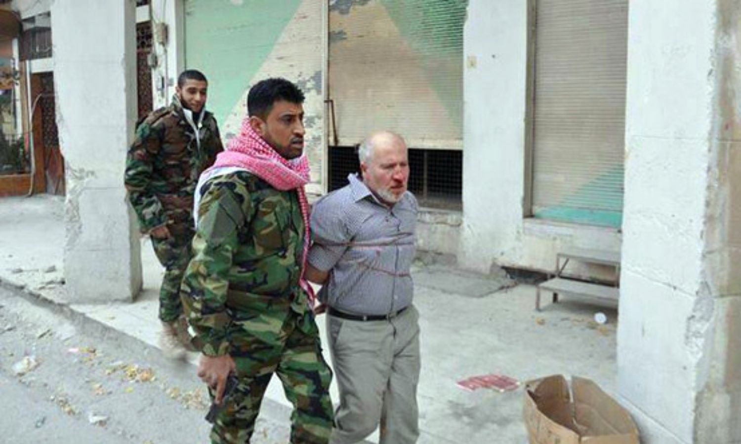 قائد ميليشيا "ذو الفقار"، أبو شهد الجبوري عراقي الجنسية، يقود مسنًّا مُكبّلًا يدعى منير عبد الحي في مدينة النبك- كانون الأول 2013 (متداول)