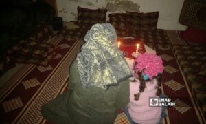 سيدة وابنتها في منزلهم بريف درعا تعتمدان على إنارة الشموع خلال ساعات 