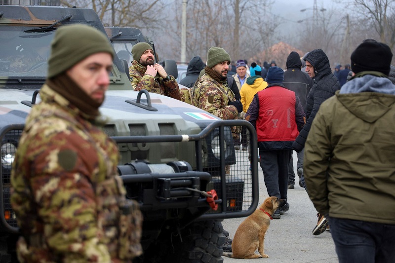 أفراد من القوات المسلحة الإيطالية تابعون لقوات حفظ السلام (KFOR) في كوسوفو، ينظرون إلى محتجين صرب بالقرب من الجزء الشمالي من بلدة ميتروفيتشا المقسمة عرقيًا، كوسوفو، 22 من كانون الأول 2022 (رويترز)