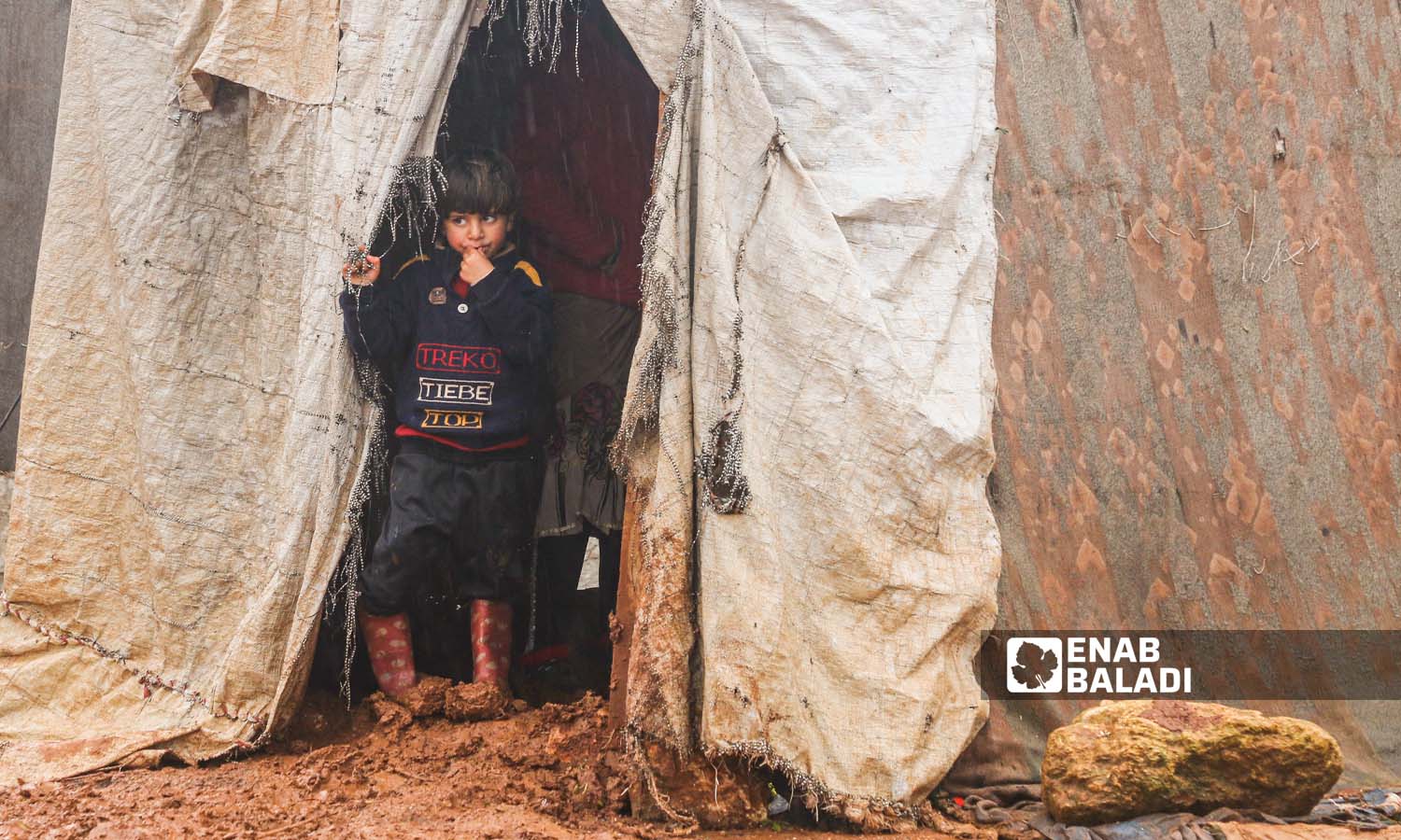 طفل يقف أمام خيمة في مخيم النور بقرية كفتين  في ريف إدلب - 16 كانون الثاني 2023 (عنب بلدي/إياد عبد الجواد)