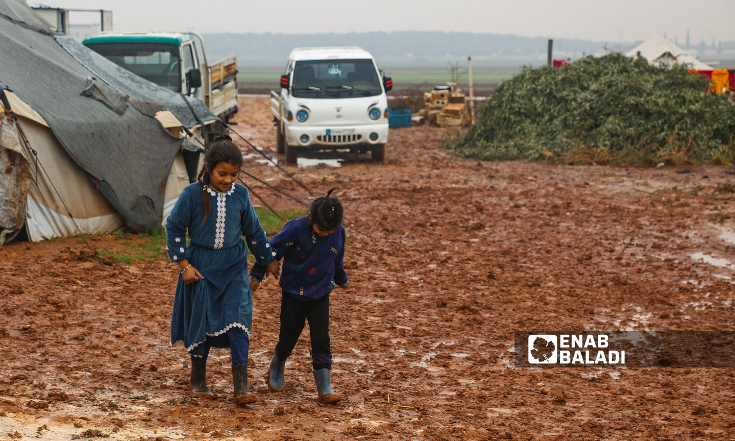 أطفال يعبرون الطريق وسط الوحل الناتج عن تساقط الأمطار في مخيم النور بريف إدلب-  16 كانون الثاني 2023 (عنب بلدي/إياد عبد الجواد)