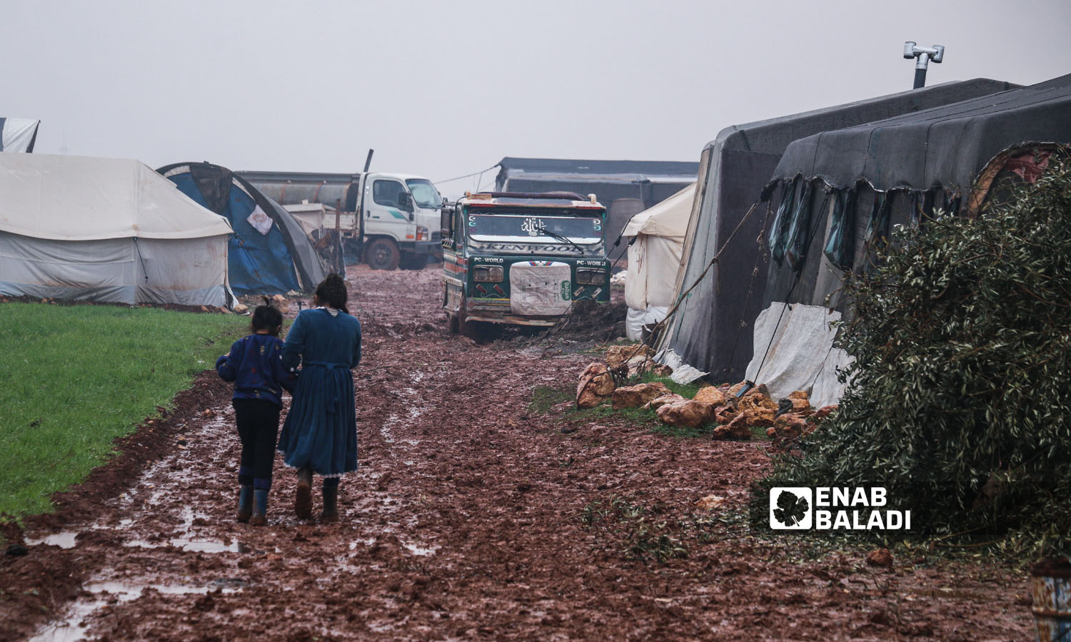 أطفال يعبرون الطريق وسط الوحل الناتج عن تساقط الأمطار في مخيم النور بريف إدلب-  16 كانون الثاني 2023 (عنب بلدي/إياد عبد الجواد)
