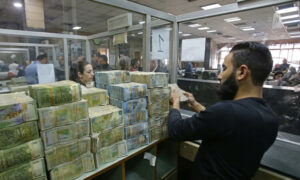 موظف يكدس أوراق نقدية من الليرة السورية في المصرف التجاري السوري بمدينة دمشق- 10 تشرين الثاني 2022 (LOUAI BESHARA/AFP)