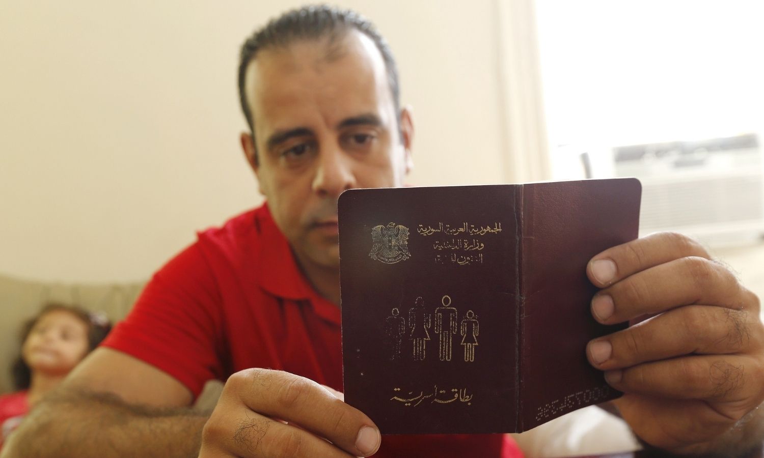 لاجئ سوري يطلع على دفتر العائلة الصادر عن وزارة الداخلية (AFP)