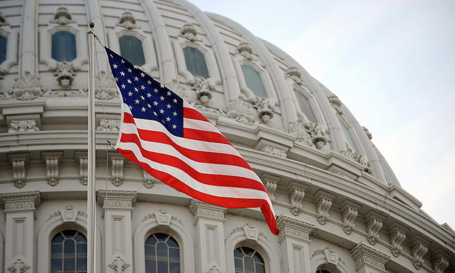 علم الولايات المتحدة الأمريكية وخلفه مبنى الـ"كابيتول" (peakpx)