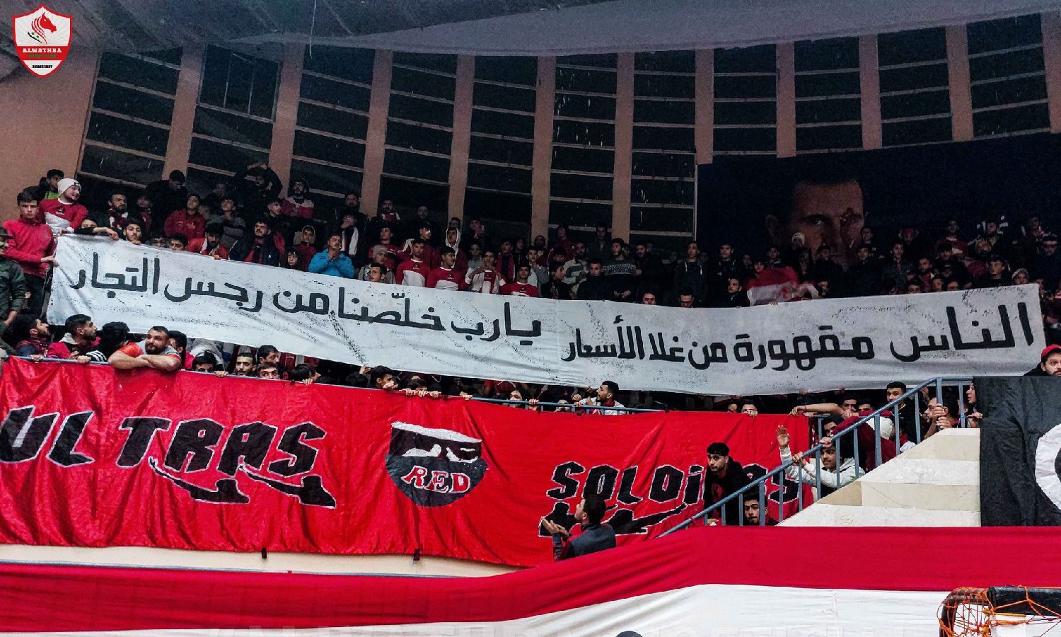 لافتة يحملها جمهور نادي الوثبة خلال مباراة كرة سلة مع نادي الكرامة في صالة "غزوان أبو زيد" بمدينة حمص- 8 كانون الثاني 2023 (نادي الوثبة الرياضي/ فيس بوك)