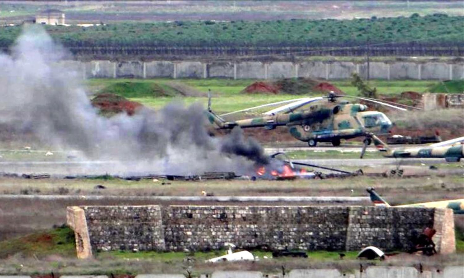 دخان يتصاعد من طائرة مروحية متضررة داخل مطار "تفتناز" العسكري بريف إدلب الشمالي الشرقي- كانون الثاني 2013 (الأناضول)