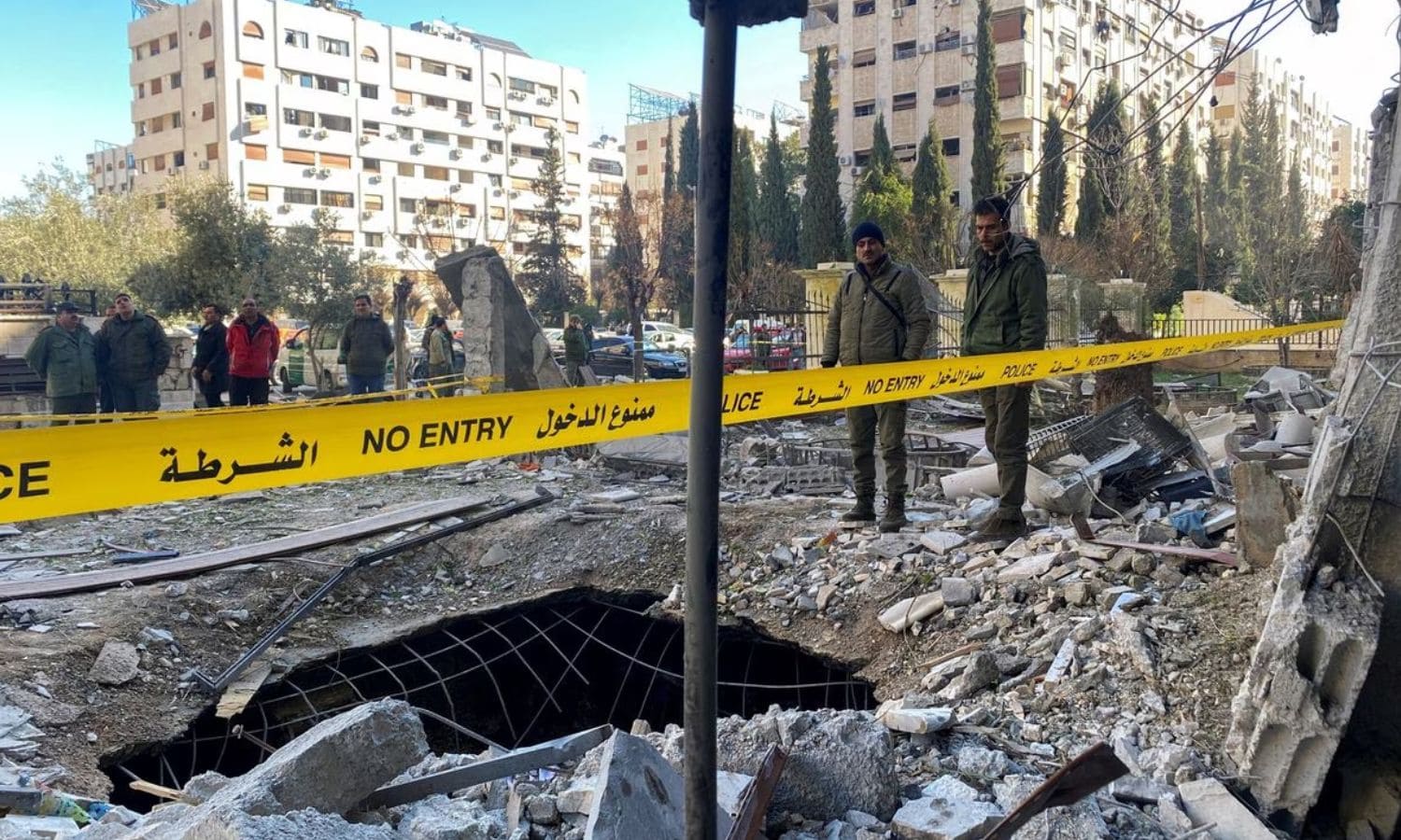 ضباط وعناصر من الشرطة والأمن يقفون وسط أنقاض مبنى مدمر في موقع هجوم صاروخي في حي كفرسوسة في دمشق- 19 شباط 2023 (رويترز)