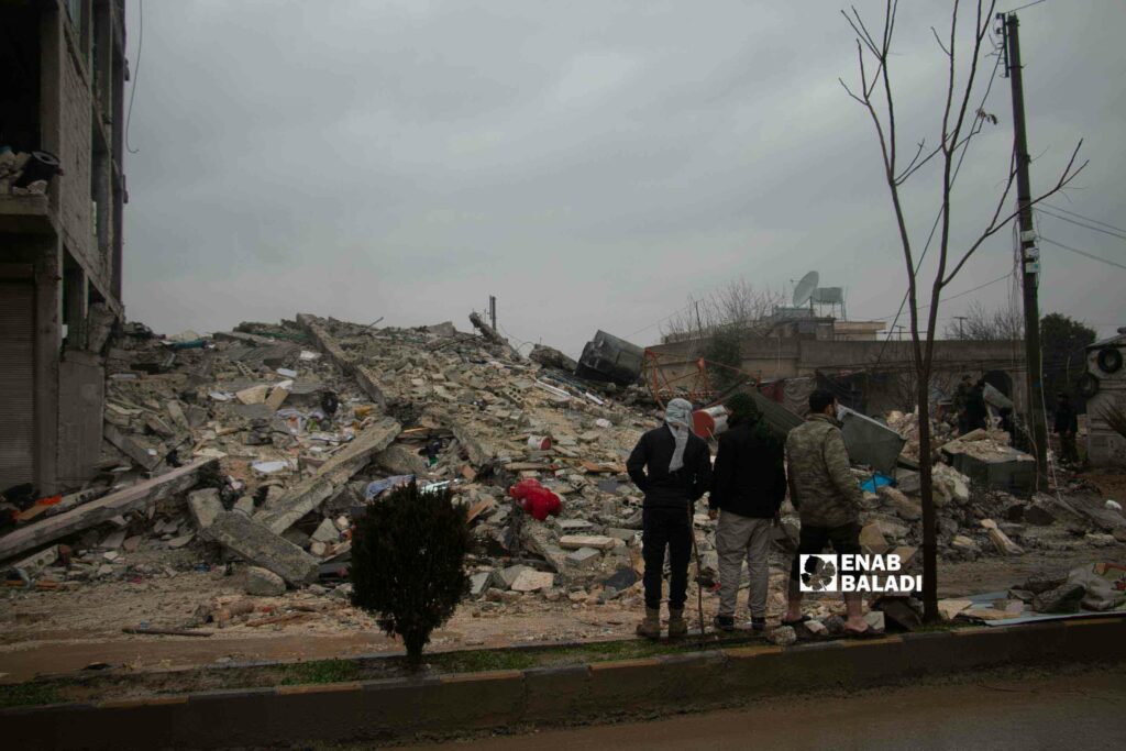 مدنيون أمام أحد الأبنية المدمرة في جنديرس بعفرين إثر زلال ضرب مناطق شمال غربي سوريا- 6 شباط 2023 (عنب بلدي/ ديان جنباز)