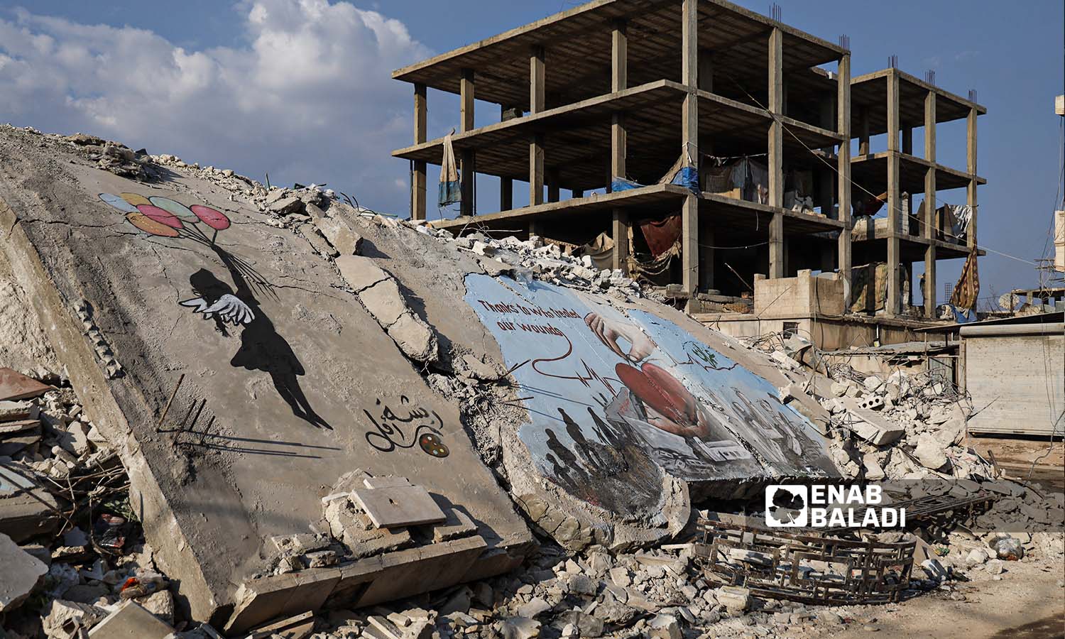  رسومات جرافيتي فوق ركام الأبنية الذي دمرها الزلزال في مدينة جنديرس بريف حلب - 24شباط 2023 (عنب بلدي/ أمير خربطلي)
