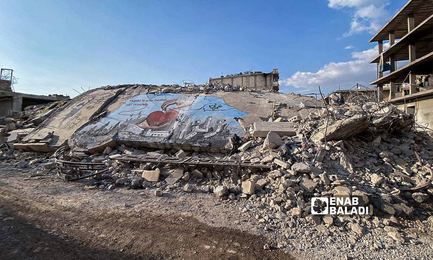  رسومات جرافيتي فوق ركام الأبنية الذي دمرها الزلزال في مدينة جنديرس بريف حلب - 24شباط 2023 (عنب بلدي/ أمير خربطلي)
