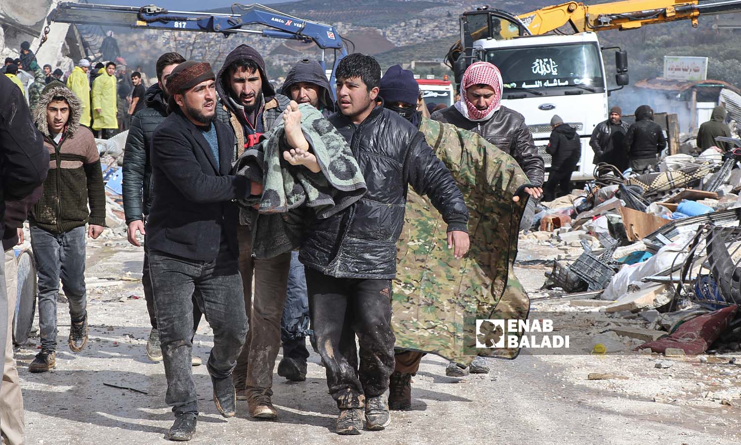 متطوعون في حارم يحملون أحد ضحايا الزلزال الذي ضرب مناطق شمال غربي سوريا - - 6 شباط 2023 (عنب بلدي/ محمد نعسان دبل)