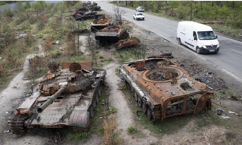 سيارات تمر من جانب دبابات روسية مدمرة في قرية دميتريفكا في كييف-(AP)