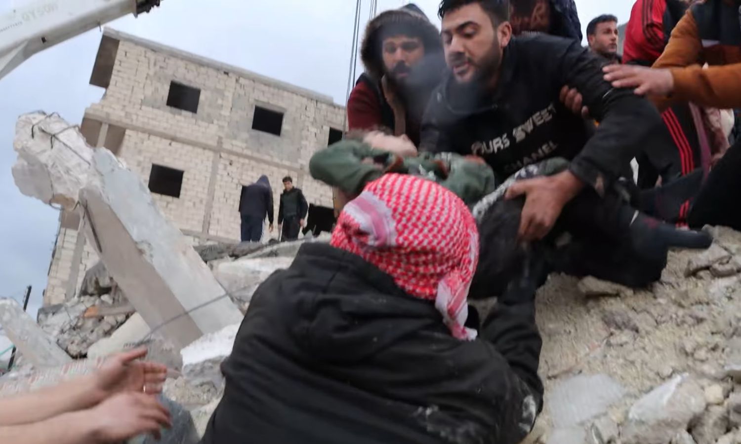 أهالي مدينة الأتارب بريف حلب الغربي يحملون طفلًا أخرجوه من تحت الأنقاض إثر زلزال ضرب مناطق شمال غربي سوريا – 7 شباط 2023 (الدفاع المدني السوري/ فيس بوك)